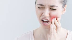 A woman with a pained expression touches her cheek, suggesting dental pain and the need for Miami cosmetic dental care.
