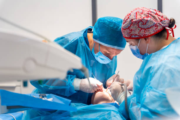 Surgeons in blue scrubs operate in a Miami clinic, showing precision like cosmetic dentists skilled in dental implants and veneers.
